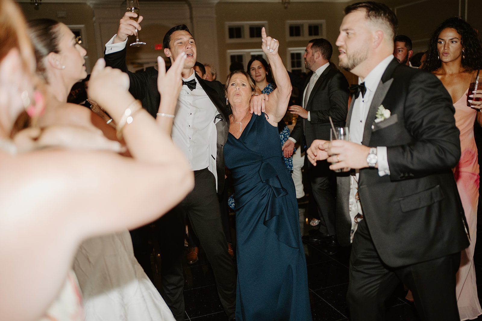 Groom's mother dancing energetically and singing along on the lively reception dance floor.